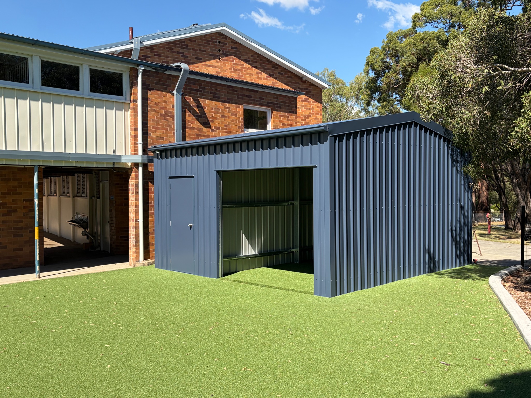 Compact charcoal storage building beside a brick facility
